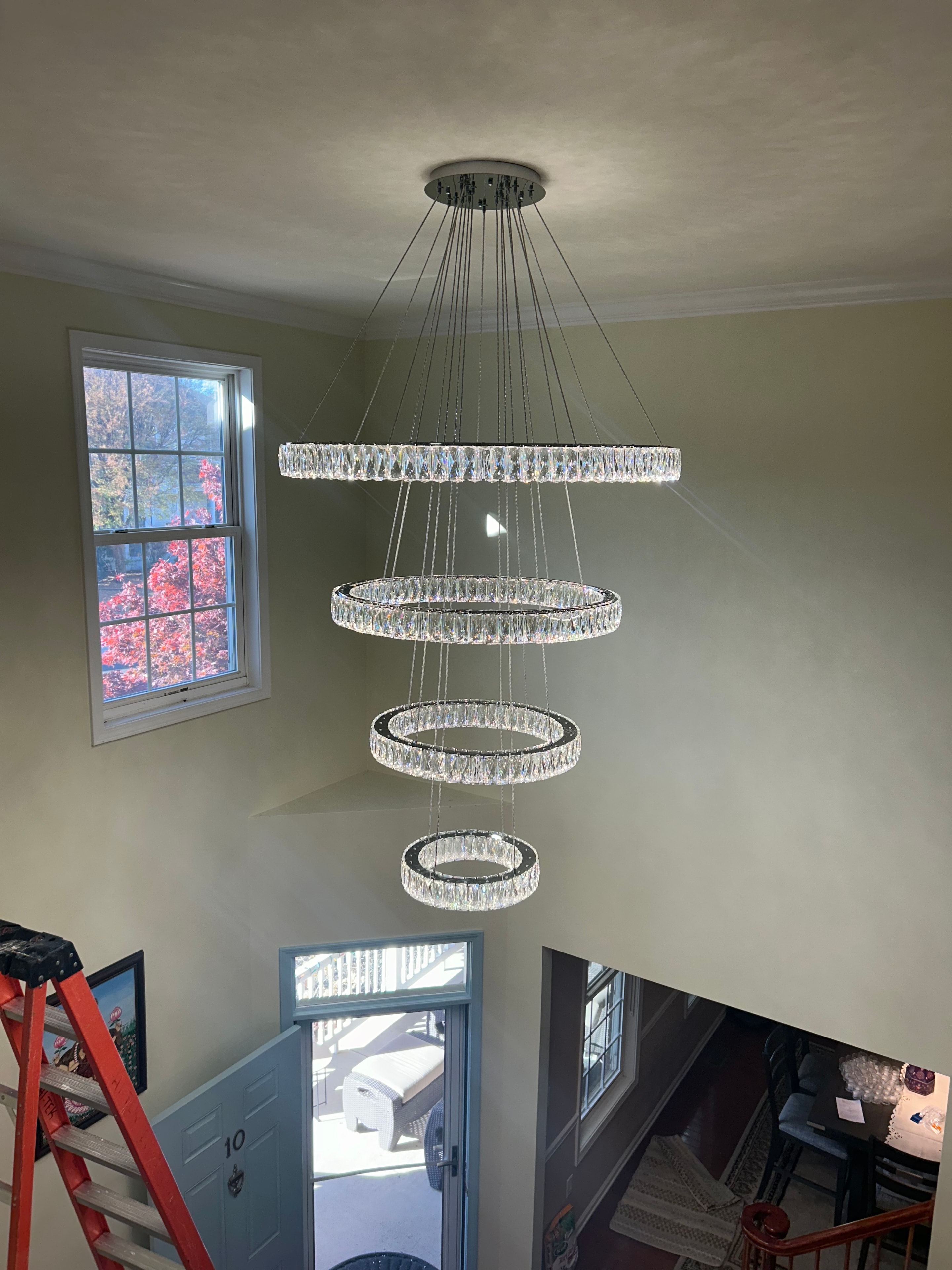 Multi-tier crystal ring chandelier installed in residential foyer stairwell