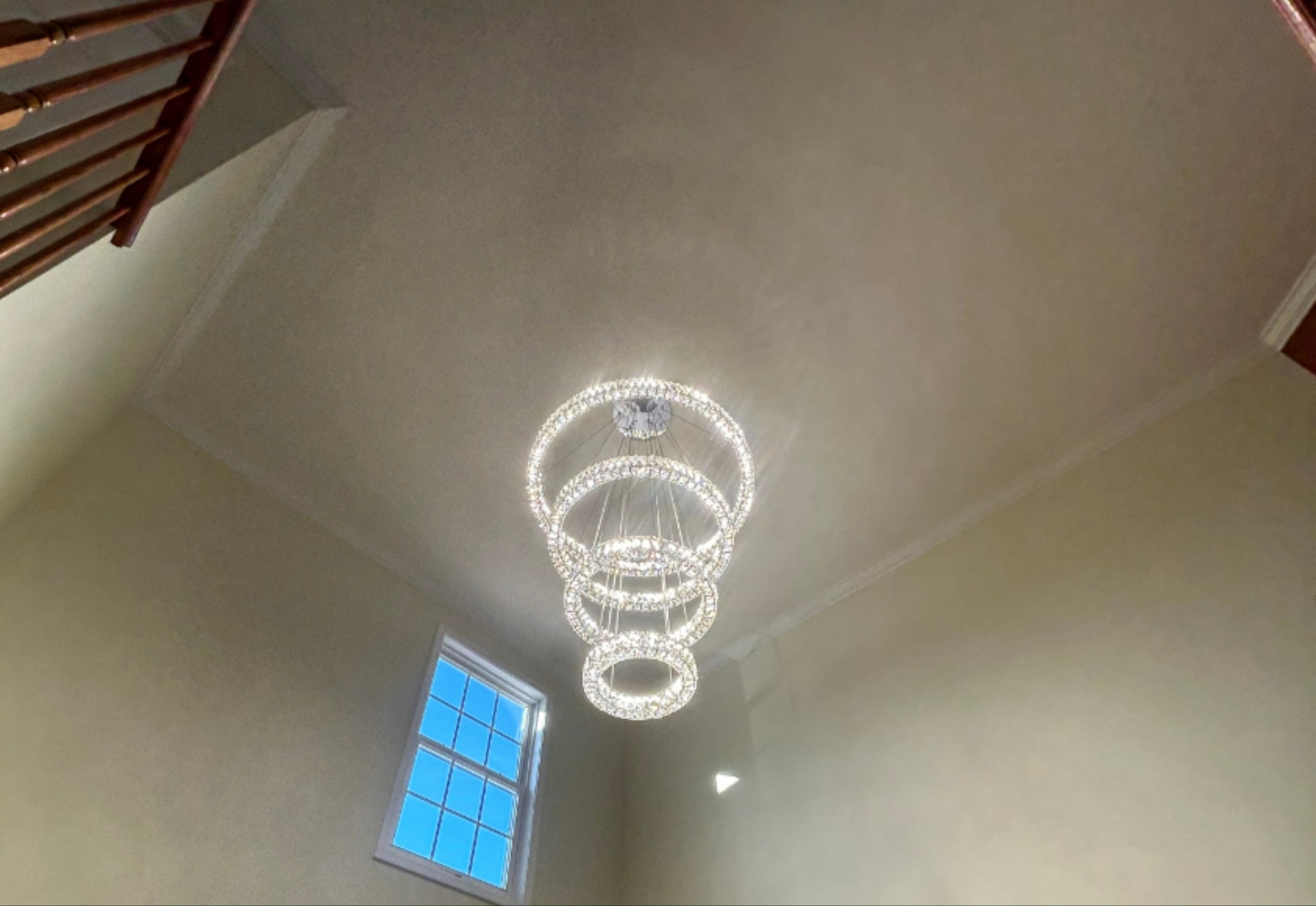 Multi-ring crystal chandelier installation in two-story foyer