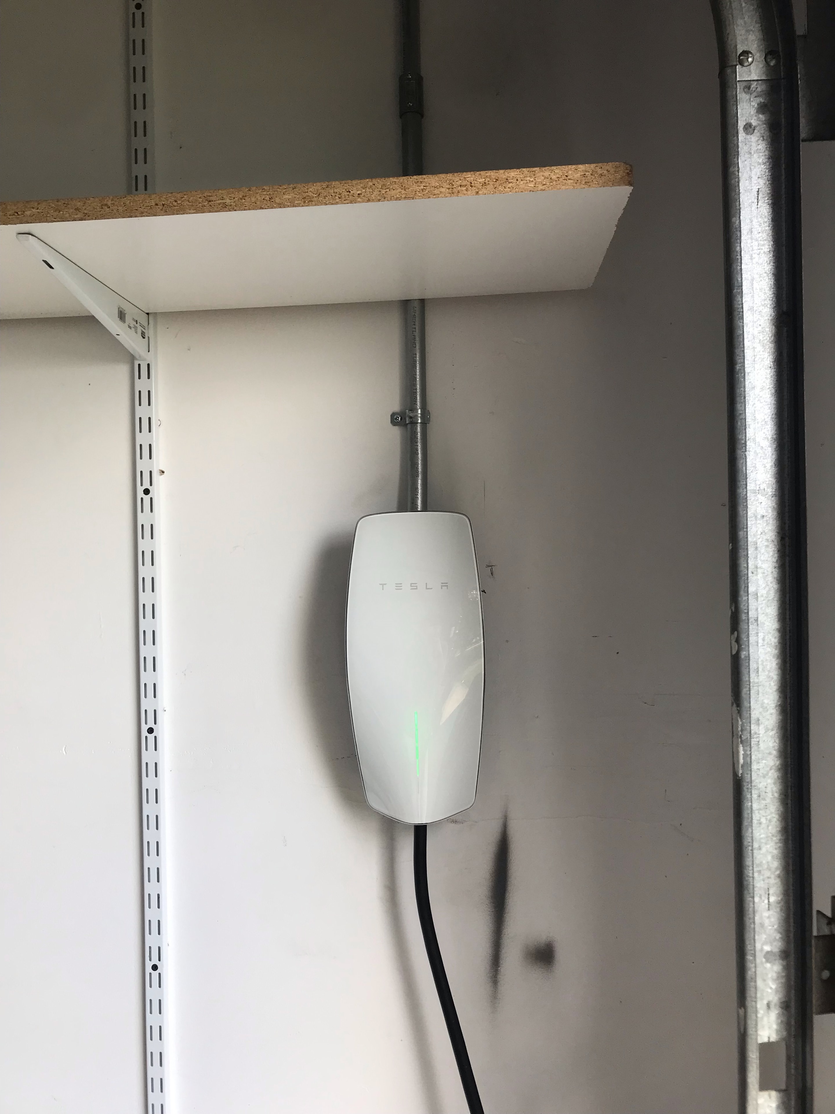 Tesla Level 2 Wall Connector EV charger mounted on garage ceiling with conduit