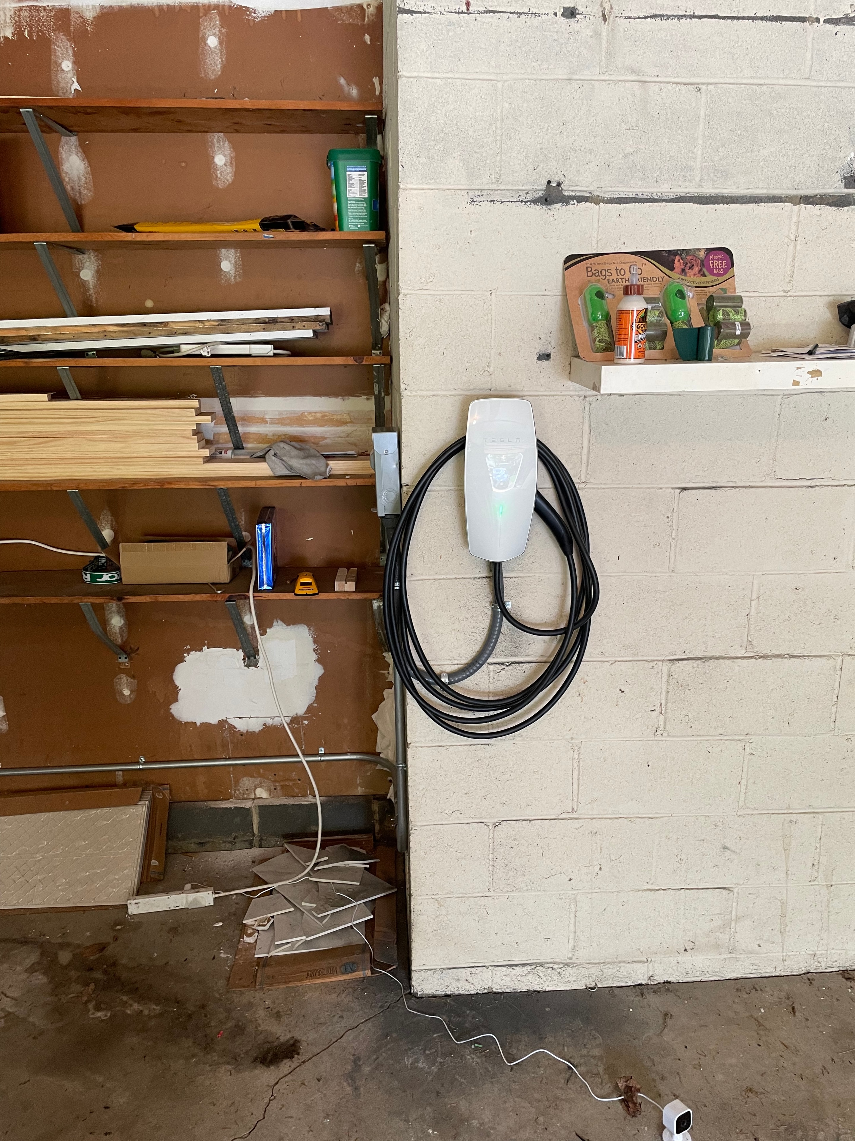 Tesla Level 2 Wall Connector EV charger installed on cinder block garage wall during renovation
