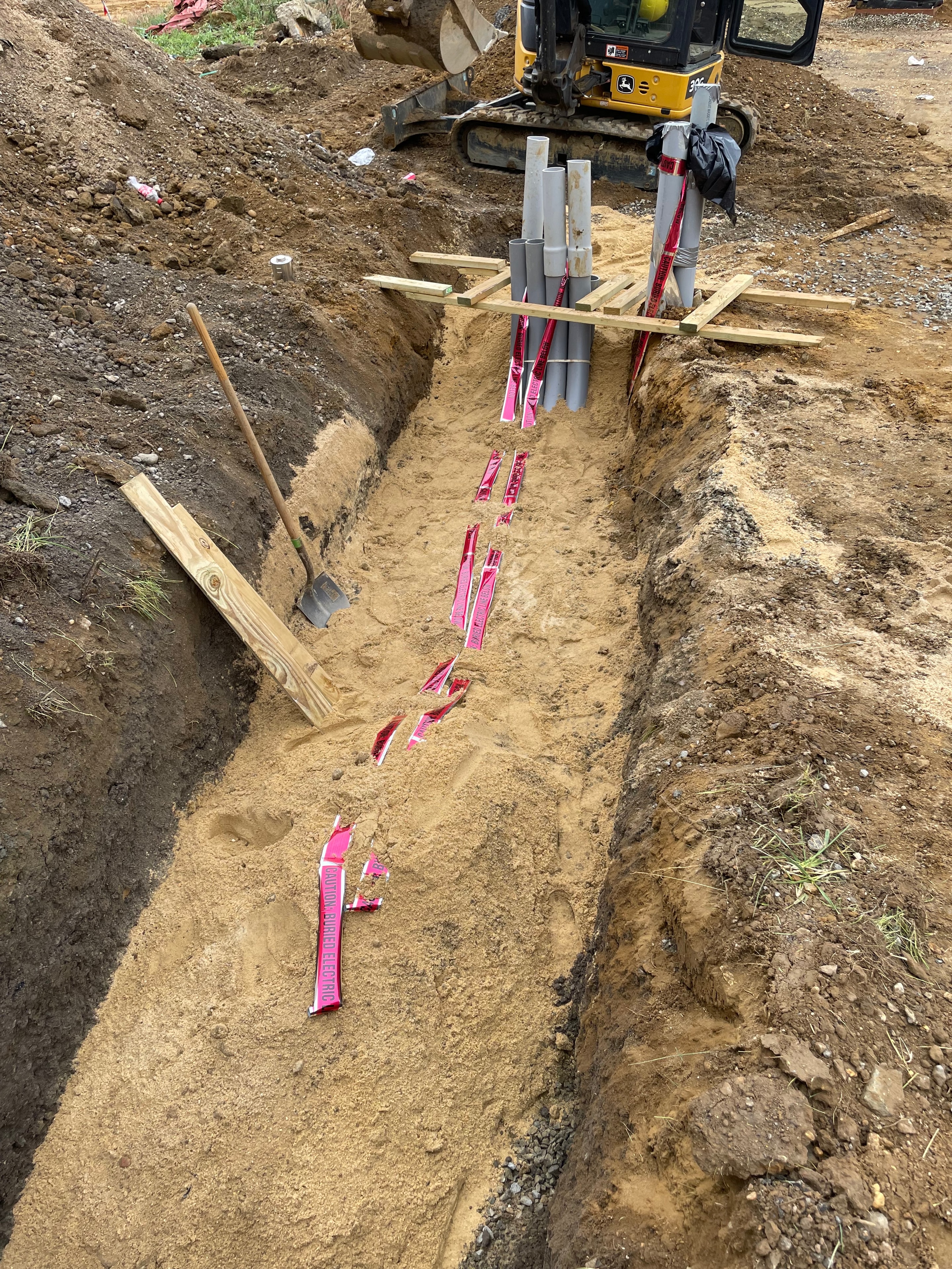 PVC conduit bundle with "Caution Buried Electric" tape laid in open trench